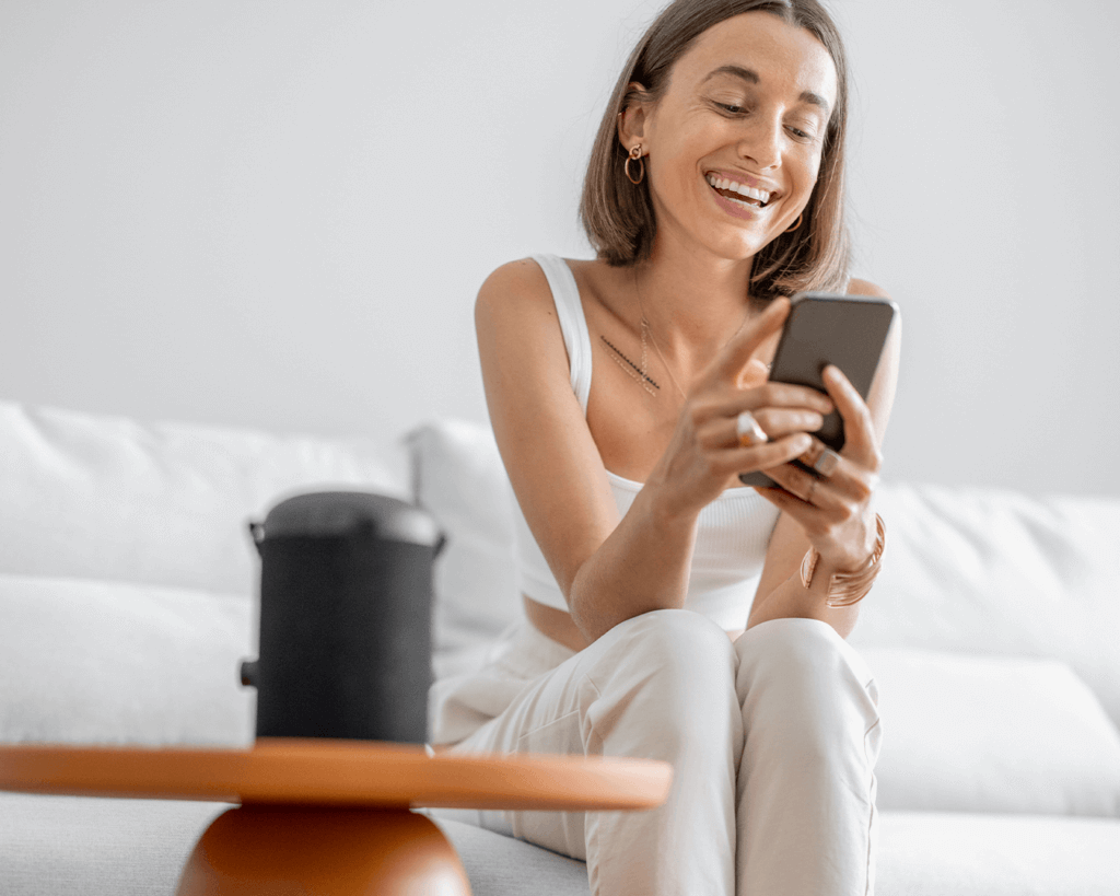 uma mulher controlando sua caixa de som pelo seu celular