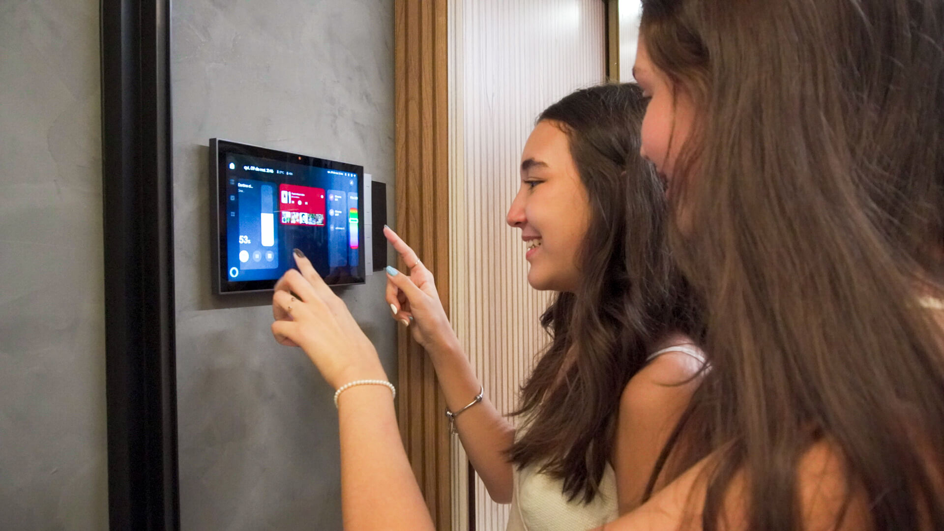 duas mulheres usando o painel de controle para controlar as automações da casa