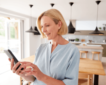 Uma senhora de idade controlando dispositivos inteligentes pelo celular